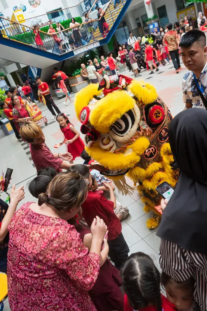 A group of people are watching a lion dance in a mall.
