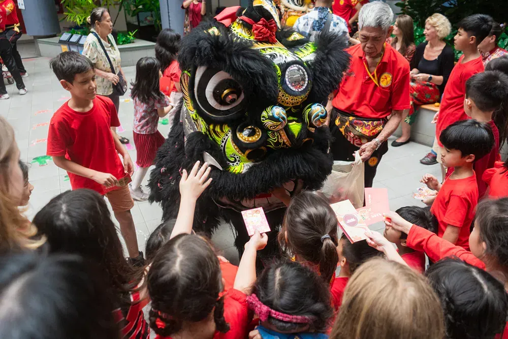 A group of children are standing around a lion costume.