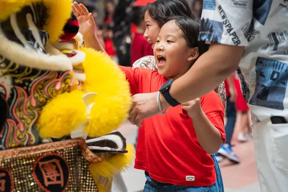 A group of children are playing with a lion costume.