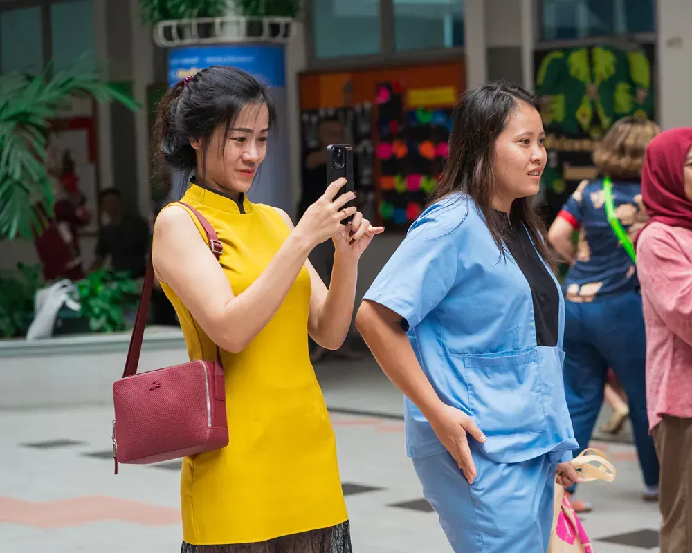 Two women are taking a picture of each other with their cell phones.