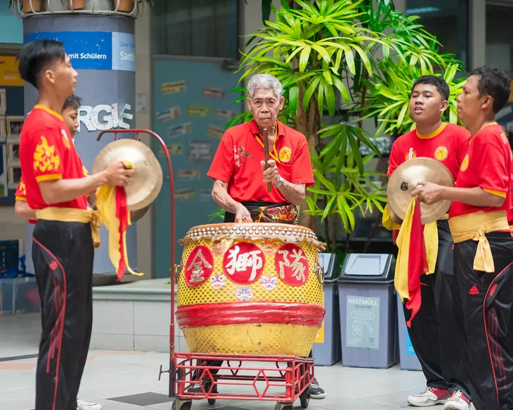 A group of men are playing drums in front of a sign that says rgs