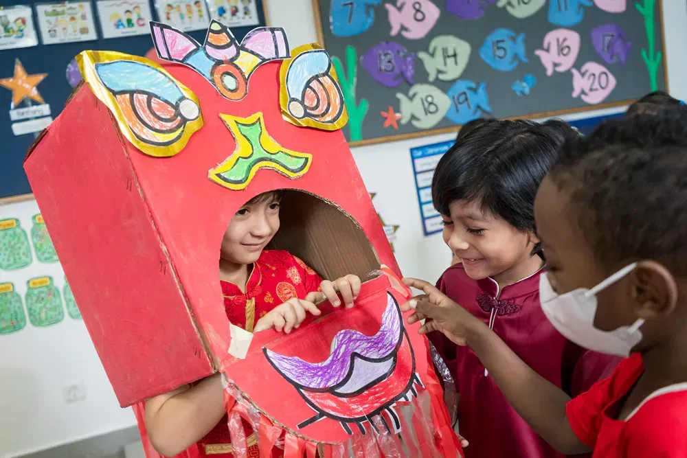 A group of children are playing with a cardboard box in a classroom.