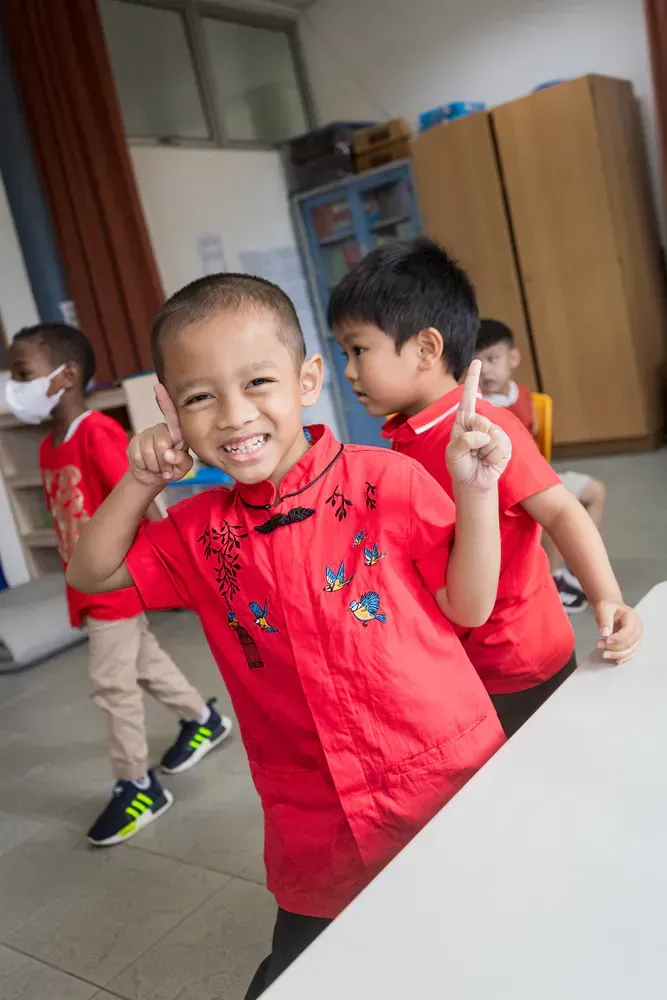 A group of young boys are standing around a table in a classroom.