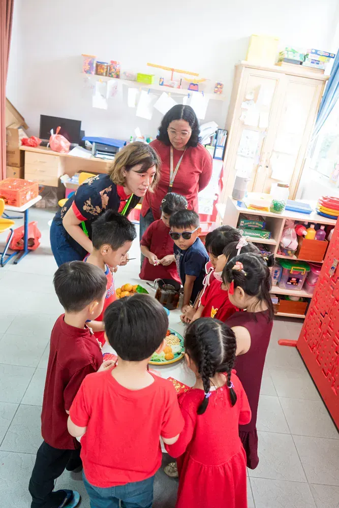 A group of children are standing around a table in a classroom.