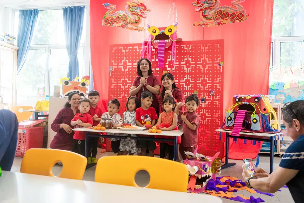 A group of children are sitting at a table in a classroom.