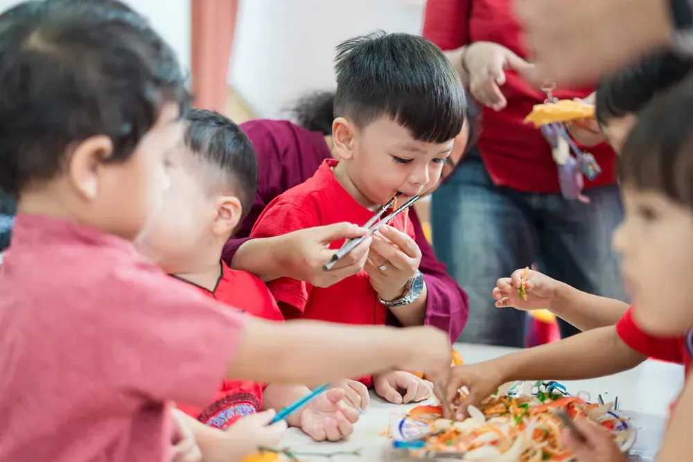 A group of children are sitting around a table eating food.