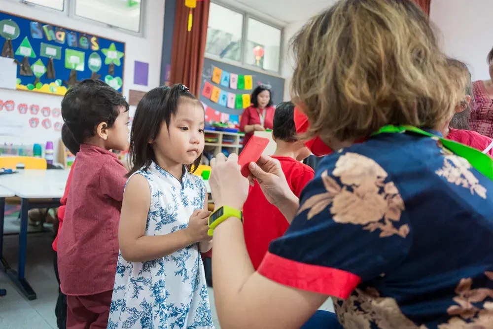 A woman is teaching a group of children in a classroom.