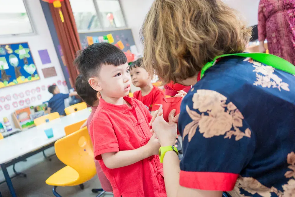 A woman is talking to a young boy in a classroom.