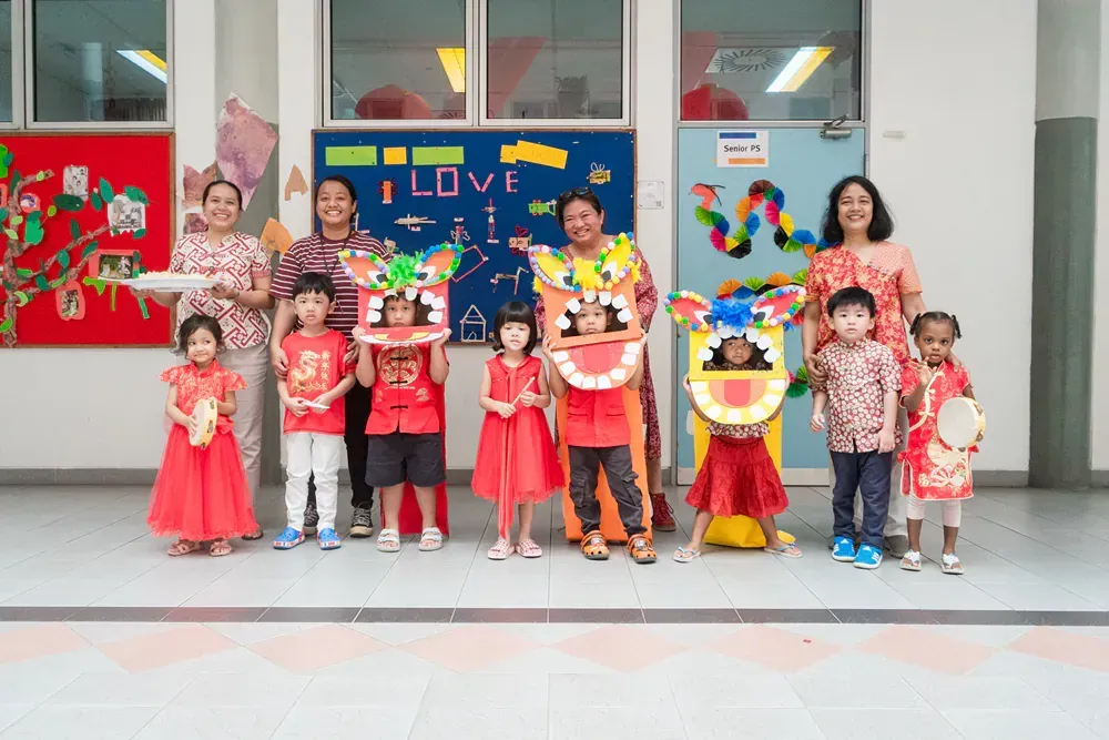 A group of children and adults are posing for a picture in a room.