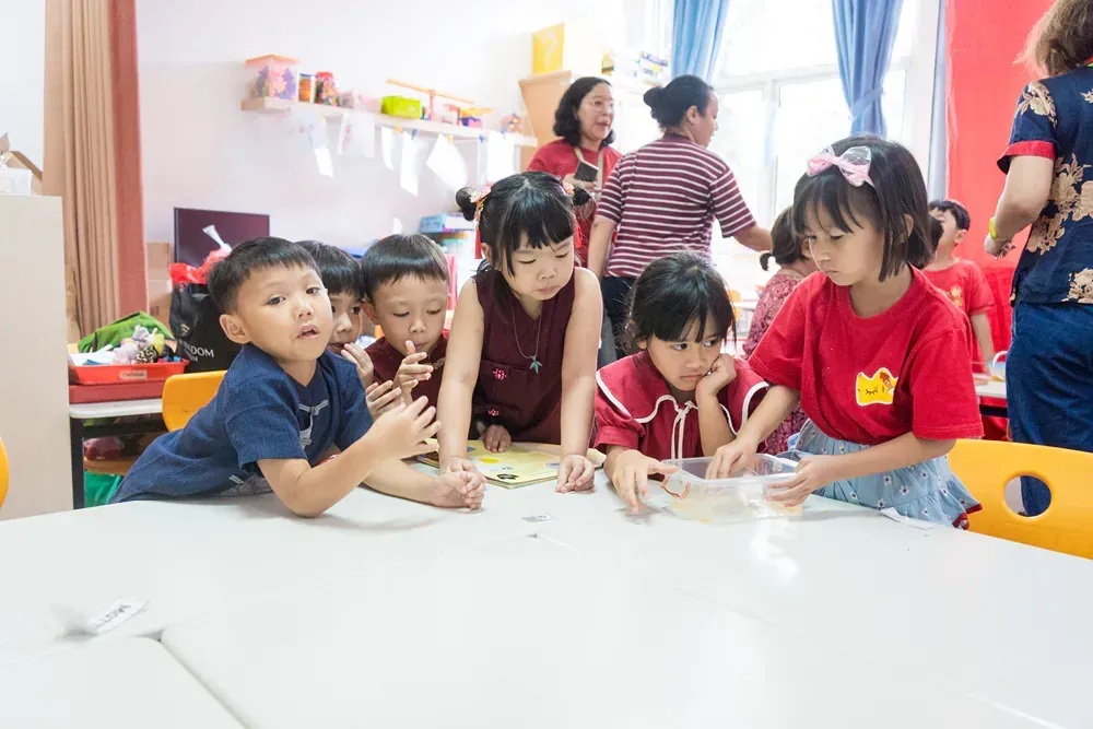 A group of children are sitting around a table in a classroom.