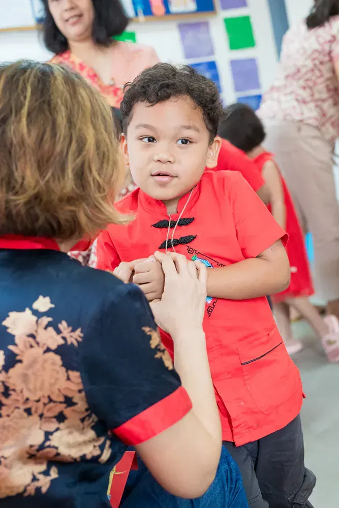 A woman is holding a young boy in her arms in a room.