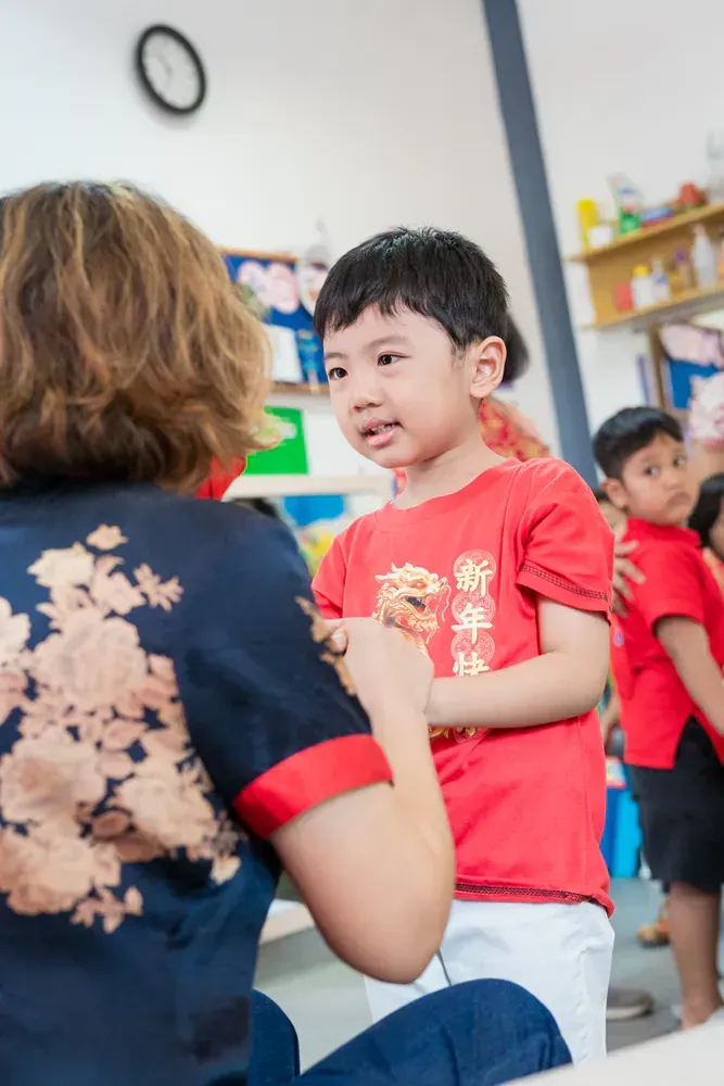 A woman is sitting next to a young boy in a red shirt.