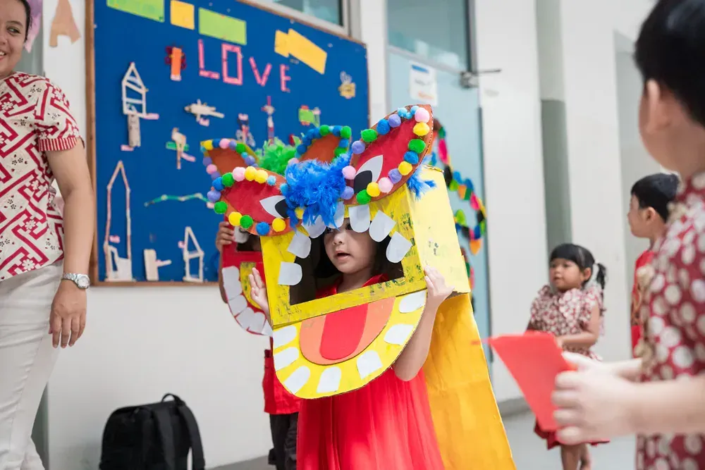 A little girl is wearing a costume made out of a cardboard box.