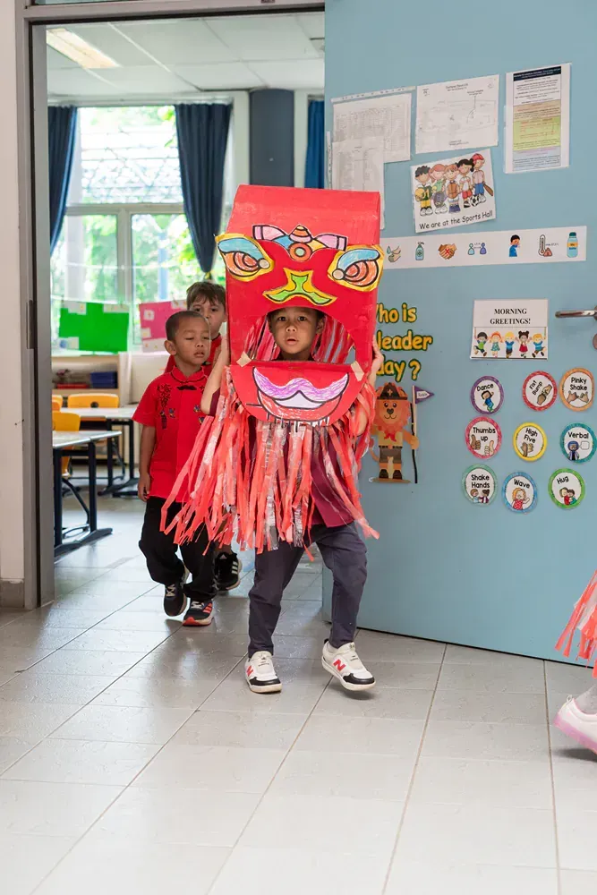 A group of children are walking through a hallway in a classroom.