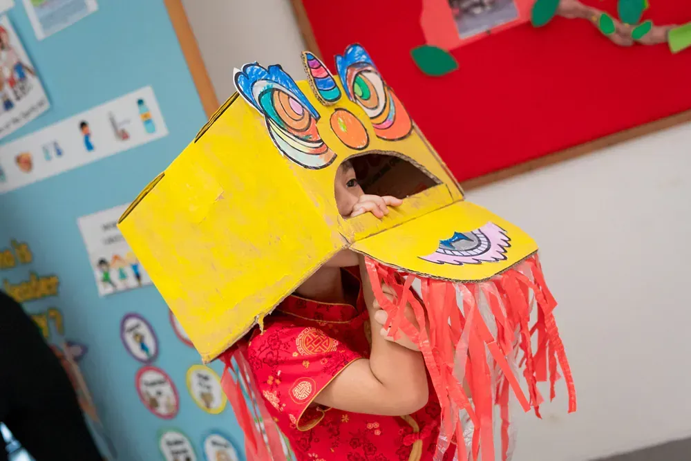 A child is wearing a costume made out of a cardboard box.