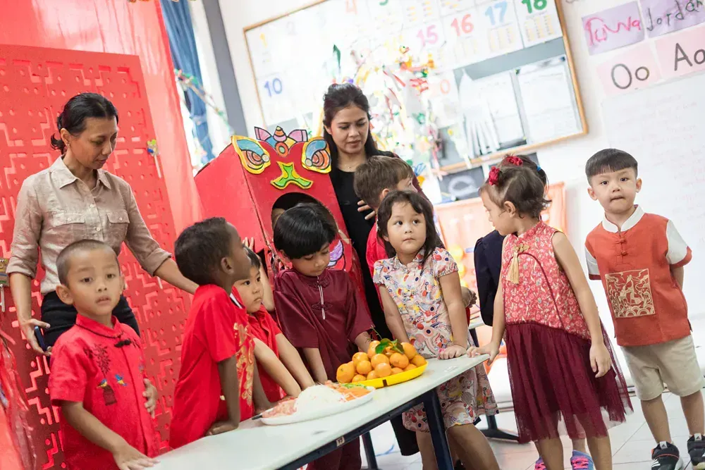 A group of children are standing around a table with fruit.