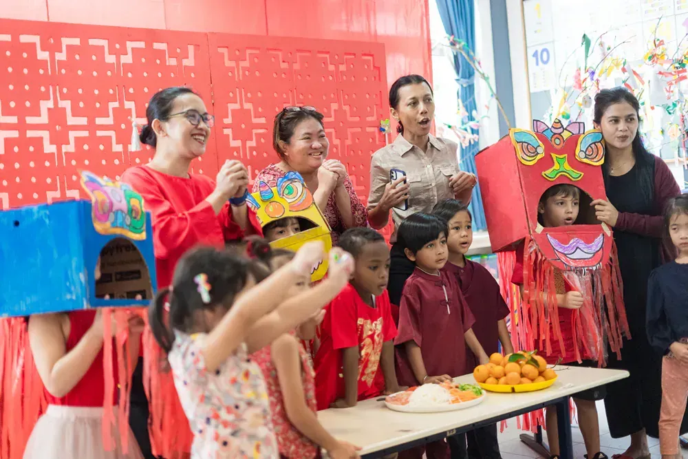 A group of children and adults are standing around a table.