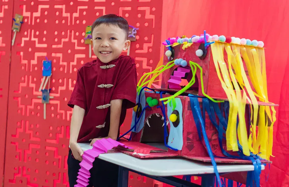 A young boy is sitting at a table with a sculpture on it.