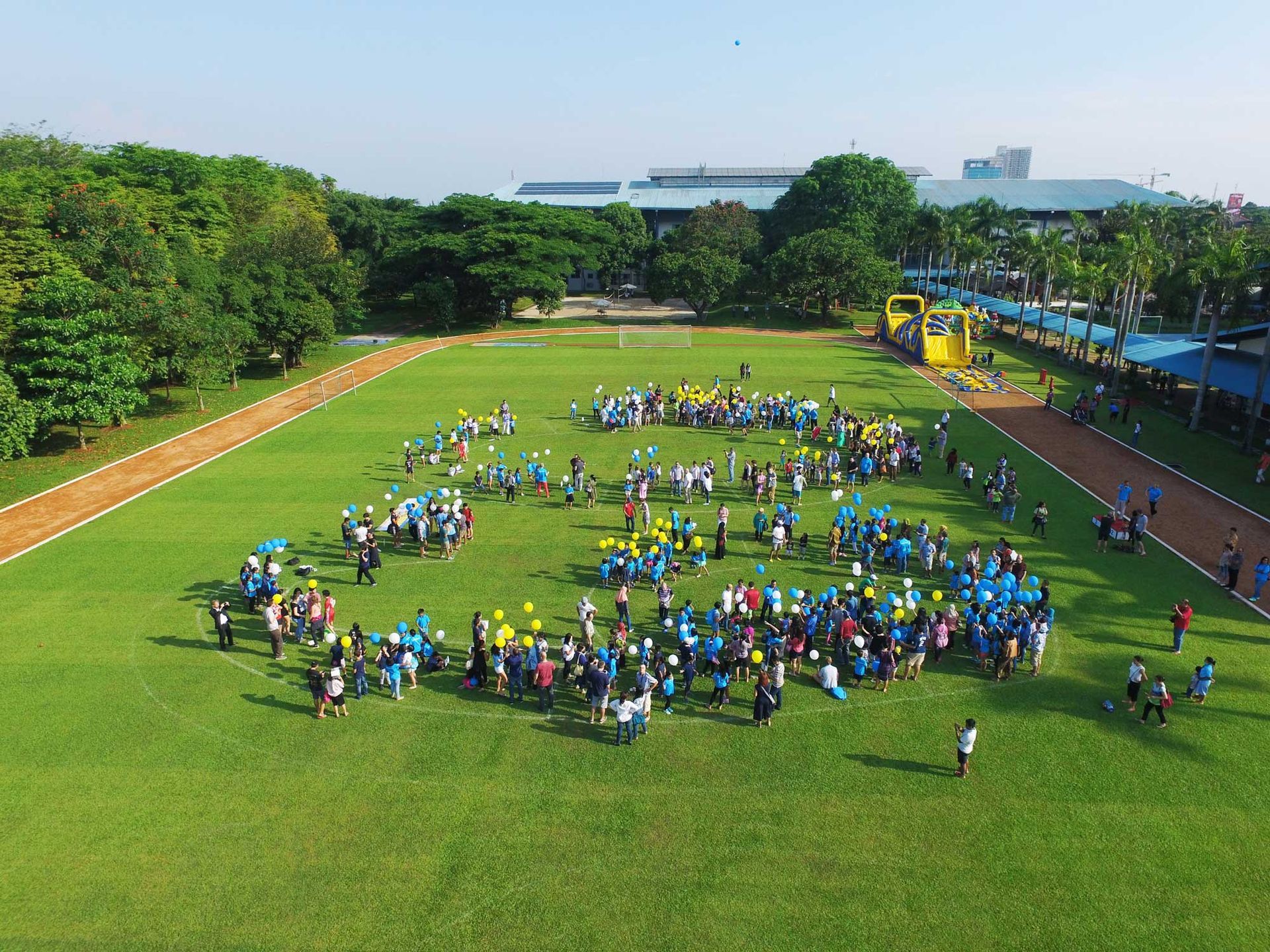 A crowd of people launching balloons on the sports field of the German School Jakarta