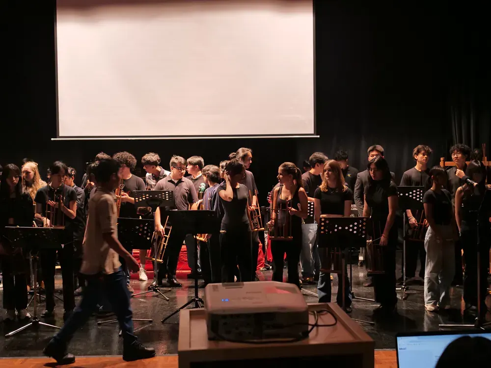 A group of people are standing on a stage in front of a projector screen.