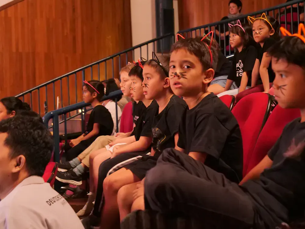 A group of children are sitting in a theater watching a performance.