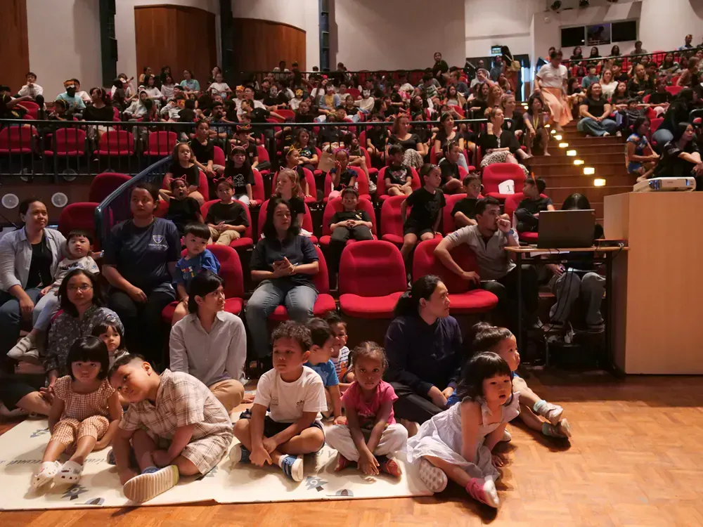 A large group of people are sitting in an auditorium watching a presentation.
