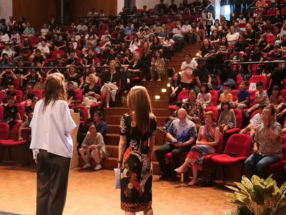 Two women standing on a stage in front of a crowd