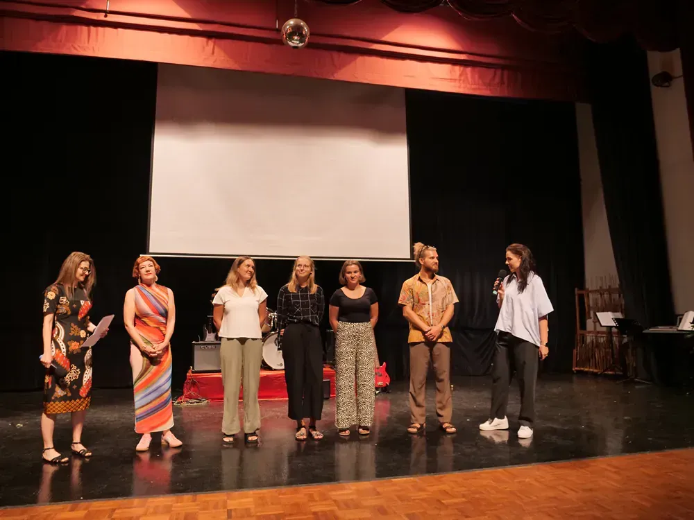 A group of people standing on a stage in front of a large screen