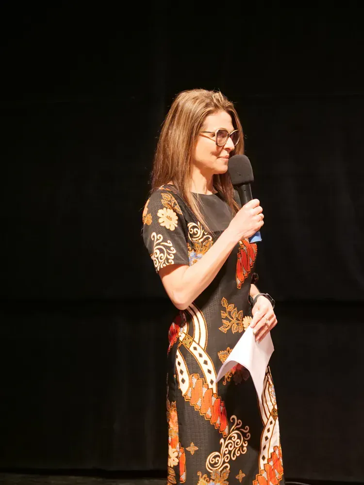 A woman in a dress is holding a microphone and a piece of paper.