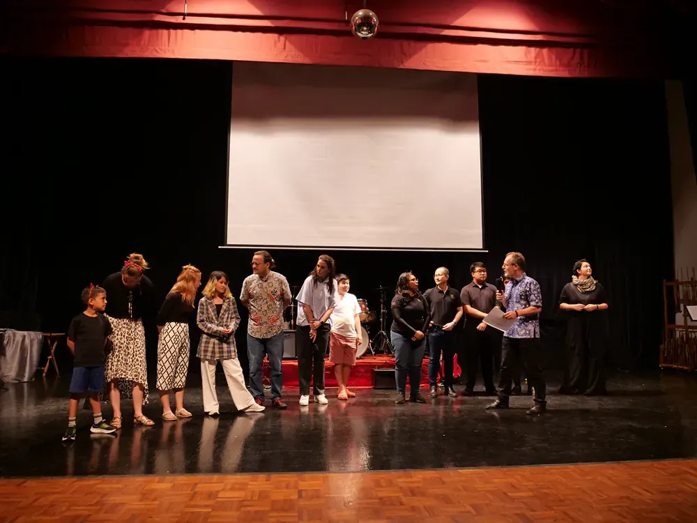 A group of people are standing on a stage in front of a large screen.