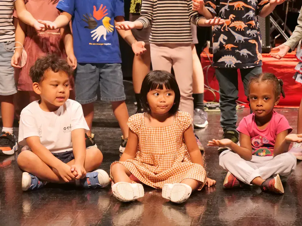 A group of children are sitting on the floor with their legs crossed