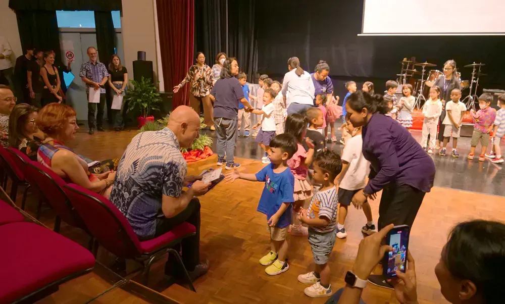 A woman is taking a picture of a group of children dancing on a stage.