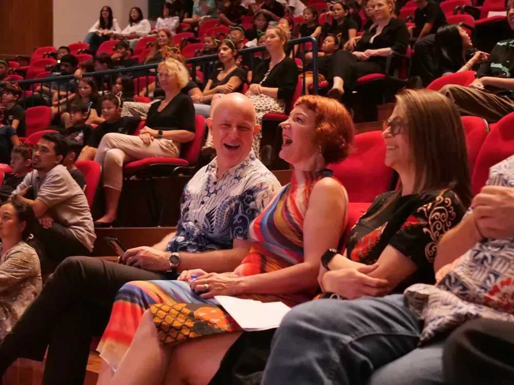 A group of people are sitting in an auditorium laughing