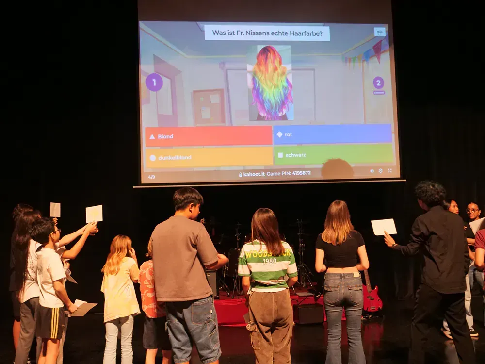 A group of people are standing in front of a large screen.