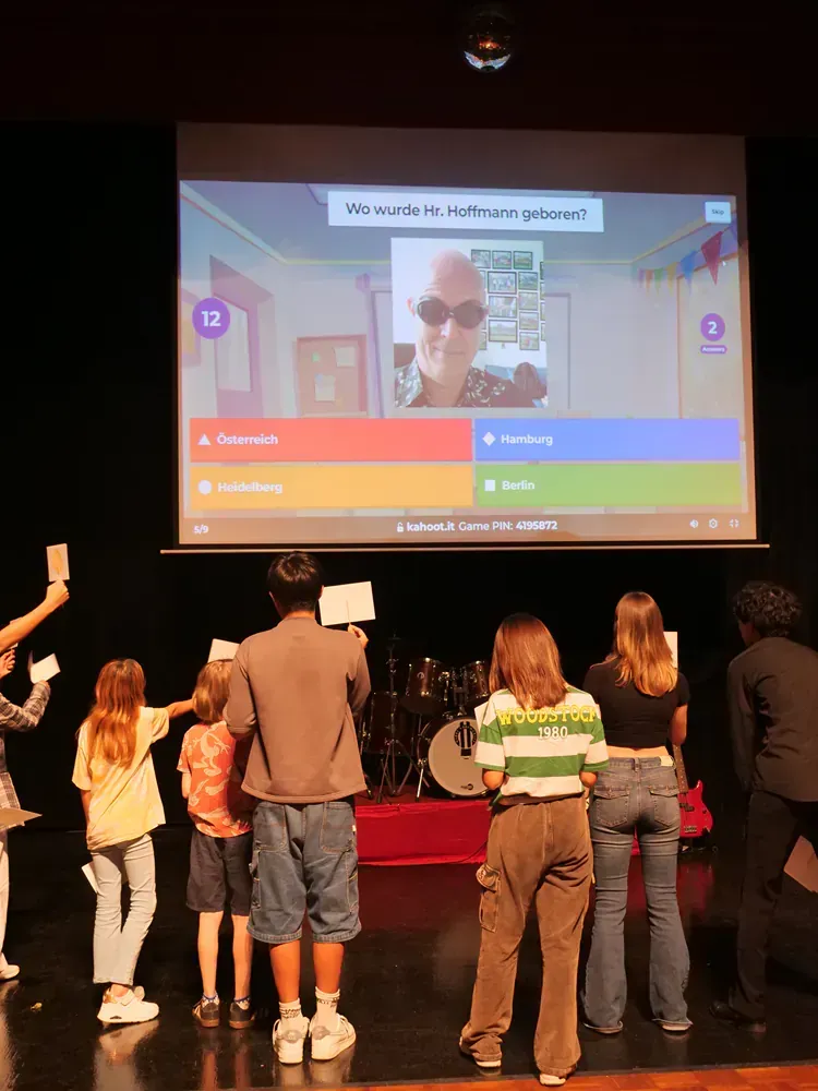 A group of people standing on a stage in front of a projector screen with the number 12 on it