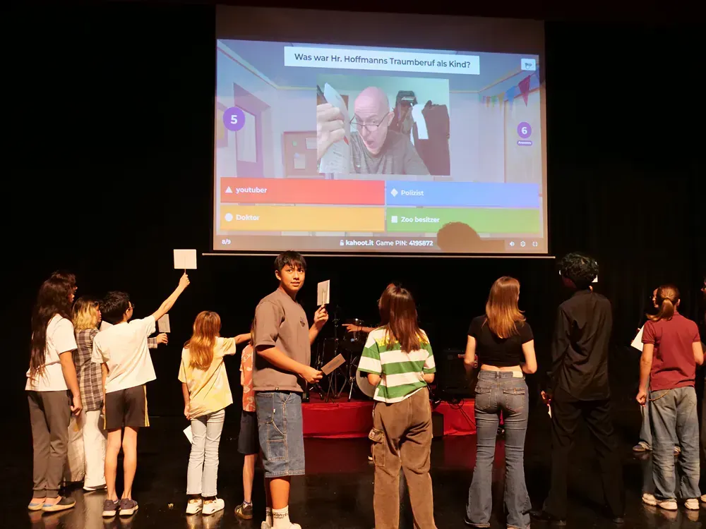 A group of children are standing in front of a projector screen.