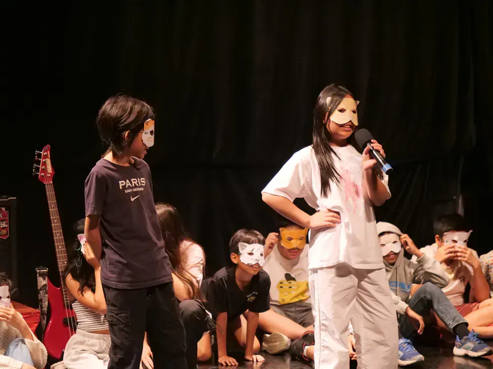 A group of children wearing masks are standing on a stage.