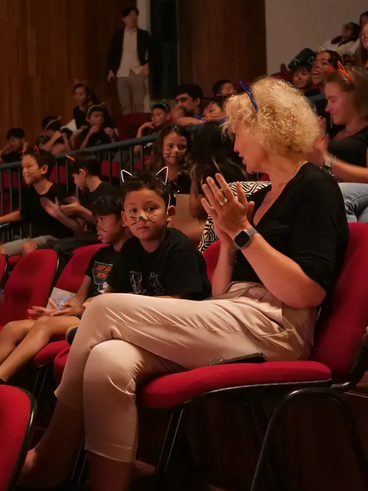 A group of people are sitting in red chairs in a theater.