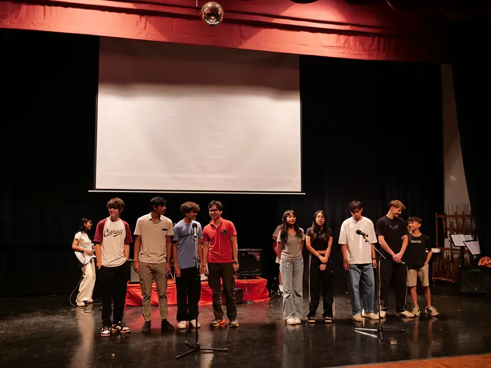 A group of people are standing on a stage in front of a projector screen.
