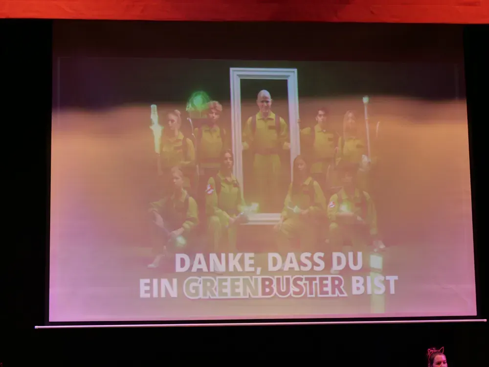 A group of people are standing in front of a projector screen.