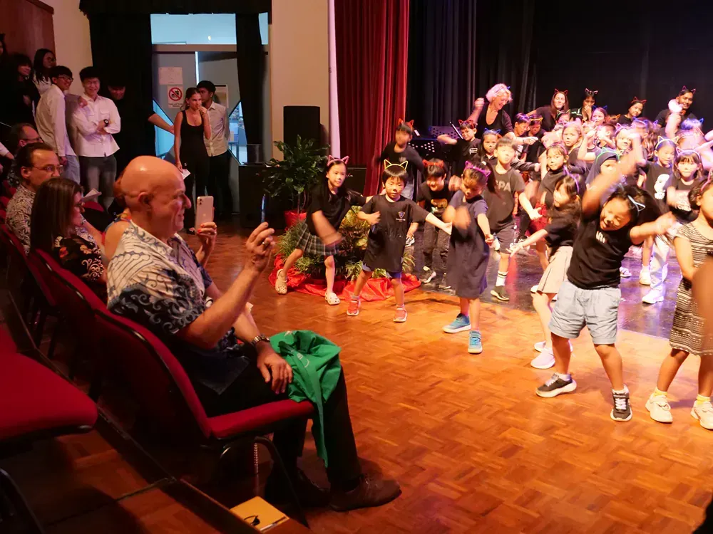 A man is taking a picture of a group of people dancing on a stage.