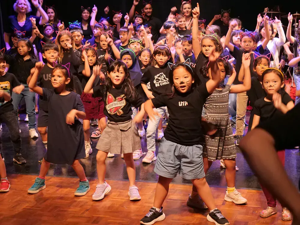 A group of children are dancing on a stage.
