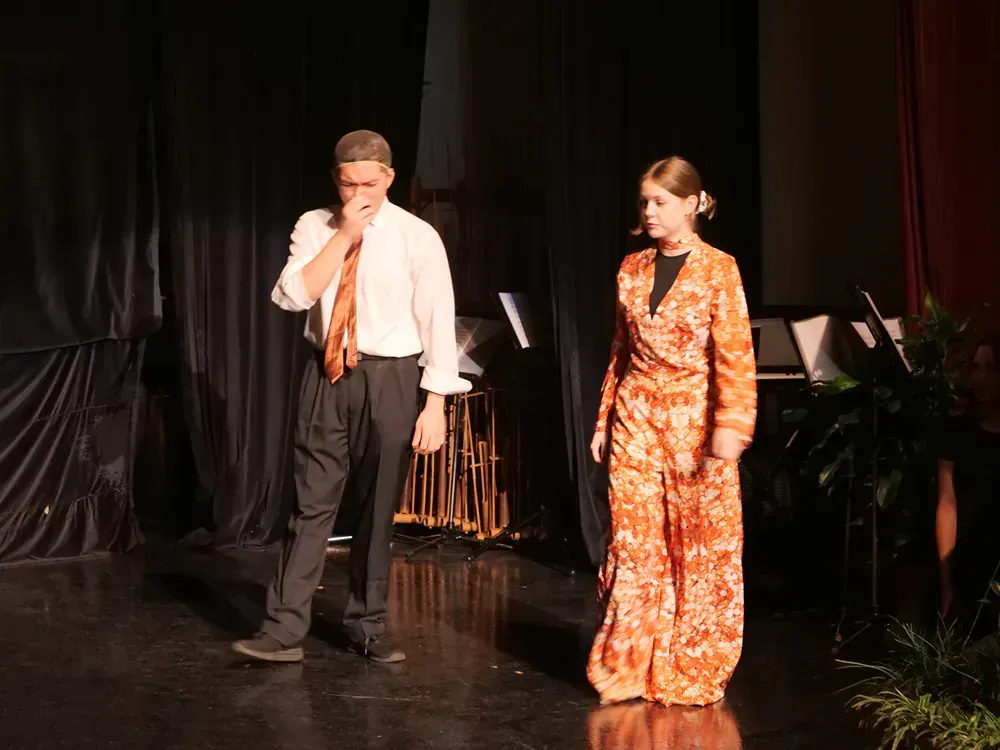 A man and a woman are walking on a stage