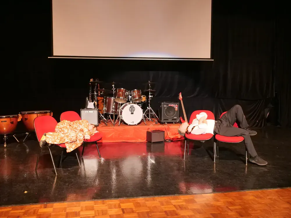 A man is laying on a chair in front of a drum set