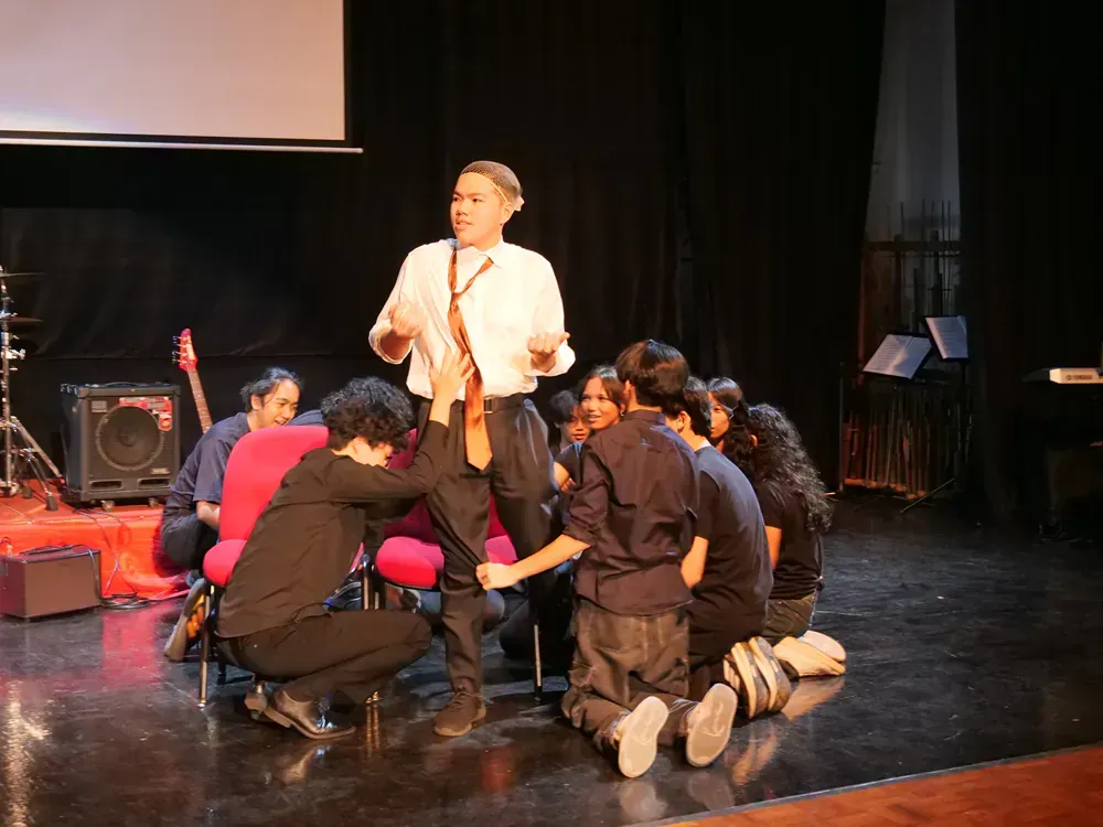 A group of people are kneeling on the floor on a stage.