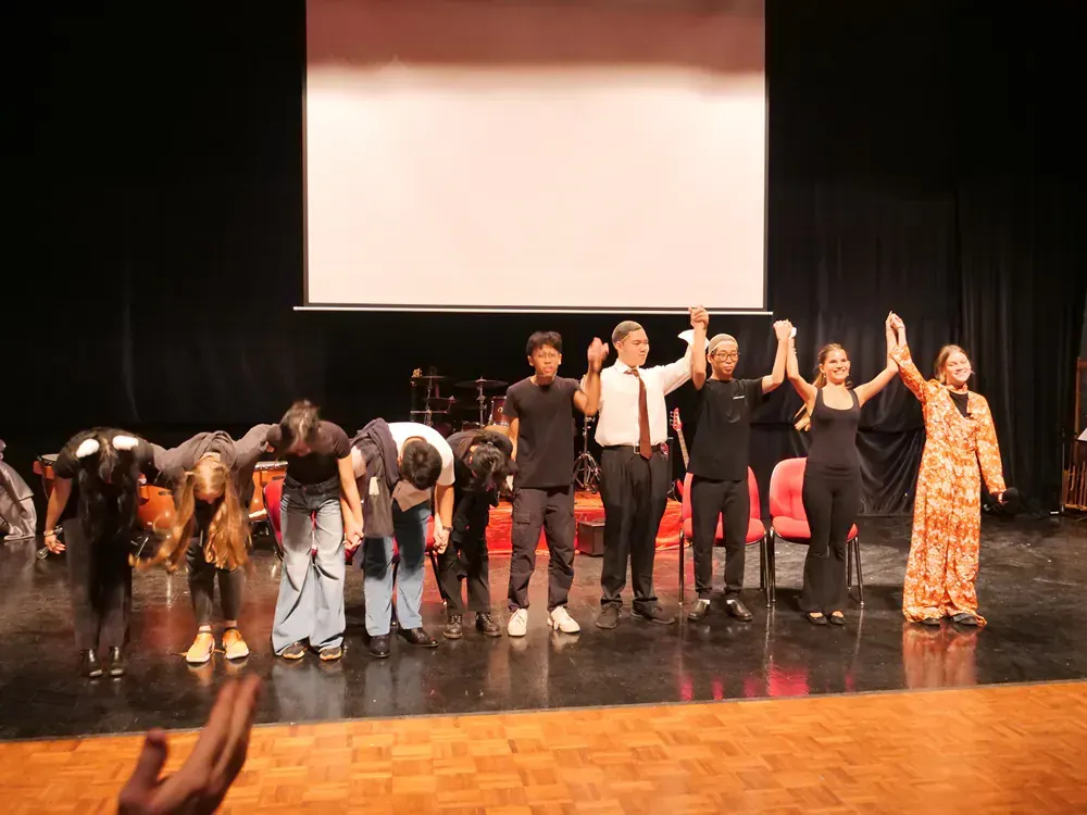 A group of people are standing on a stage holding hands.