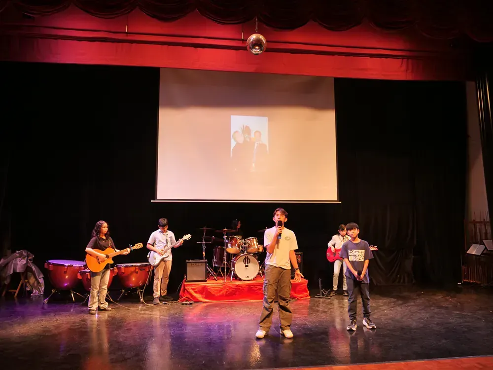 A group of people are standing on a stage in front of a large screen.