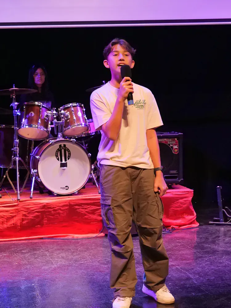 A young man is standing on a stage holding a microphone.