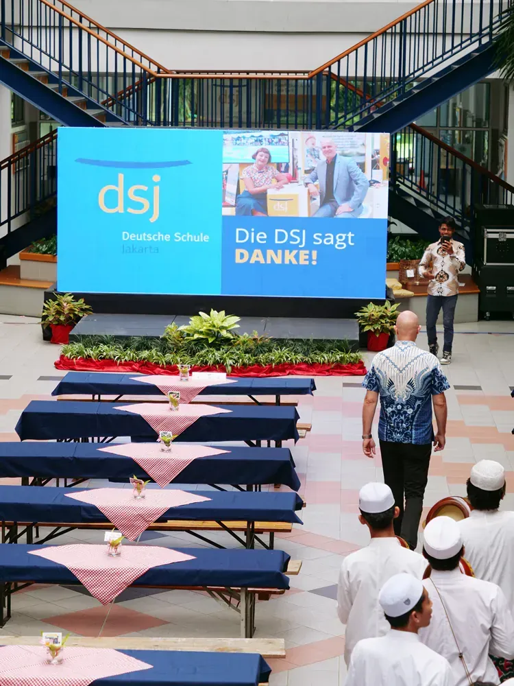 A group of people standing in front of a large screen that says dsj