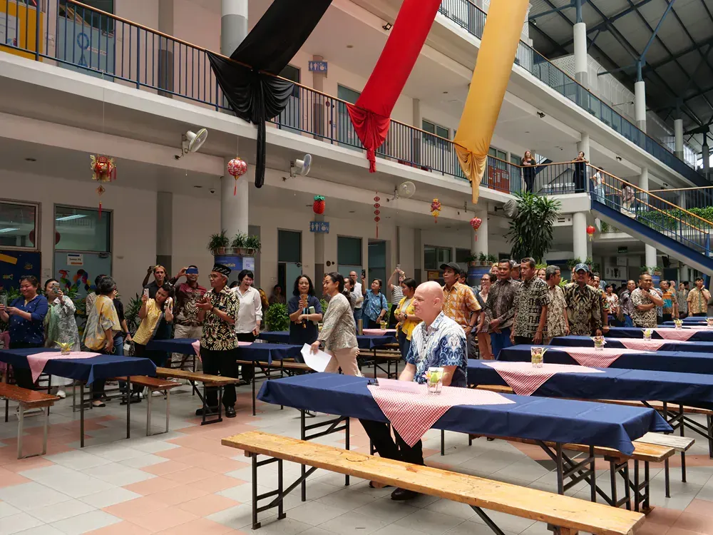A group of people standing around tables in a large building
